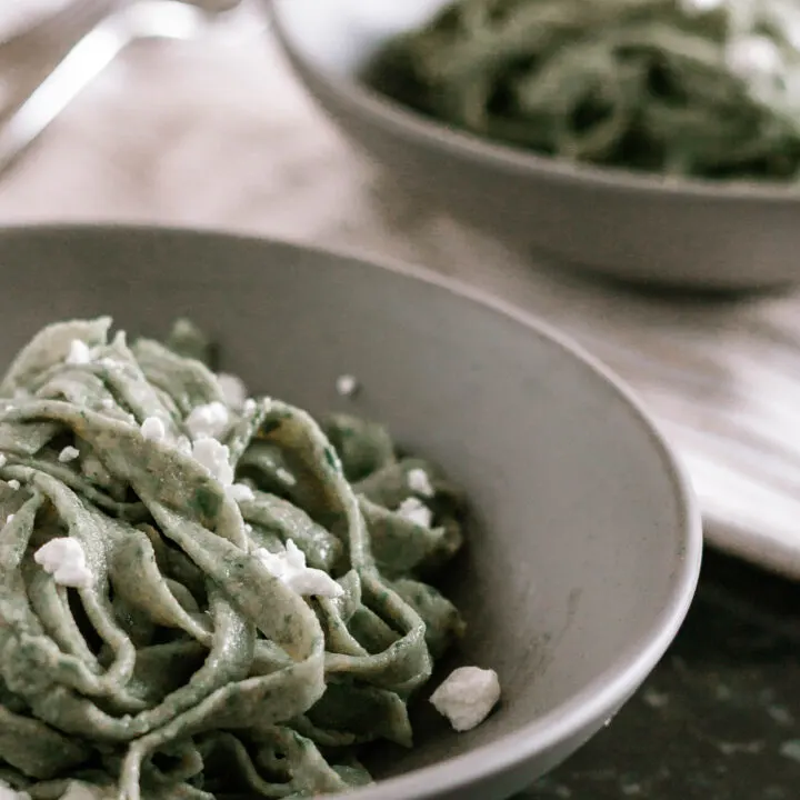 offset photo of prepared fresh spinach pasta in low grey bowls, cut into a thick noodle shape