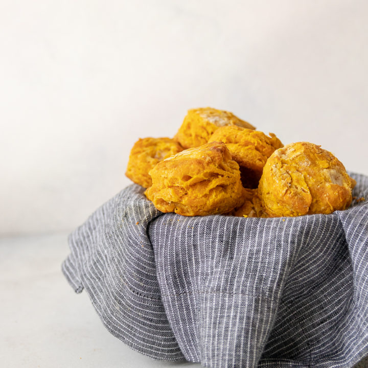 savory pumpkin biscuits in a basket lined with a grey and white pinstripe napkin