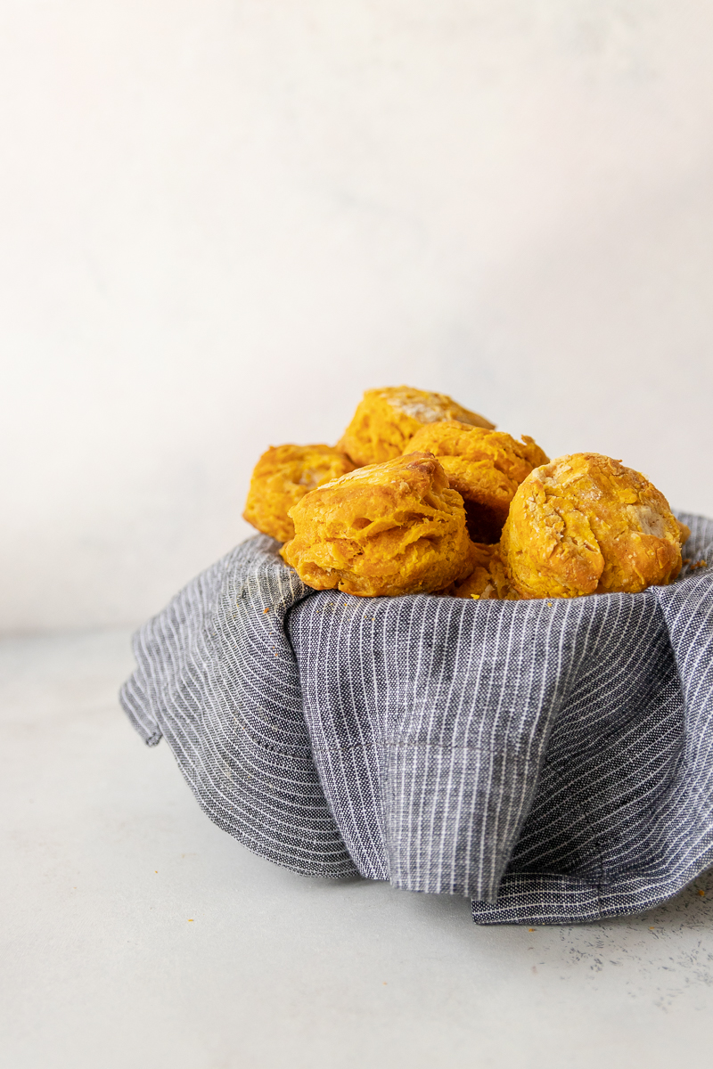savory pumpkin biscuits in a basket lined with a grey and white pinstripe napkin