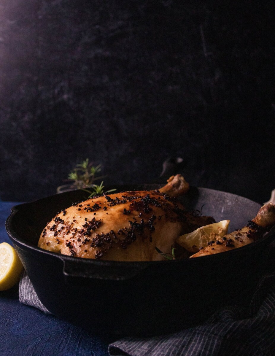 whole rosemary garlic oven roasted chicken in a cast iron skillet