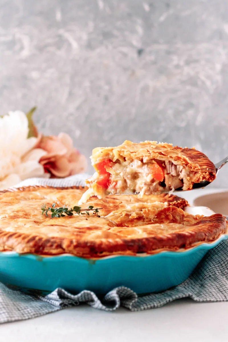 slice of turkey pot pie being lifted out of the main serving dish on a silver cake server