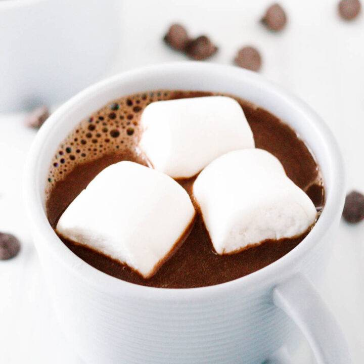 close up of the hot chocolate in a grey mug with 3 jumbo marshmallows floating on top