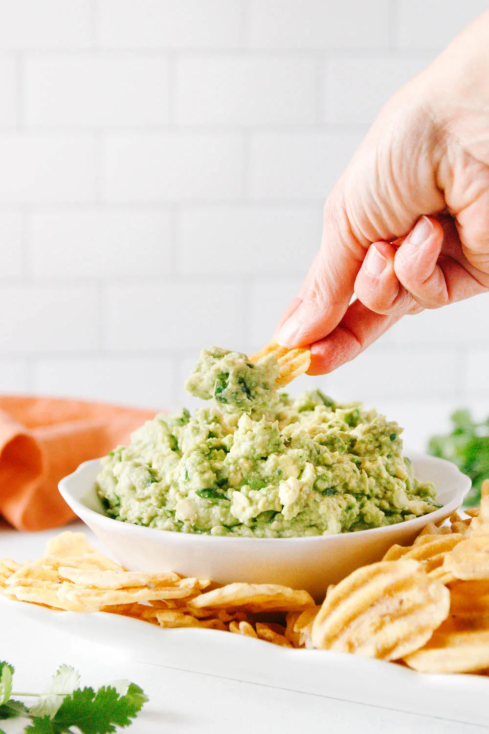 hand dipping a chip into the bowl to scoop some guacamole