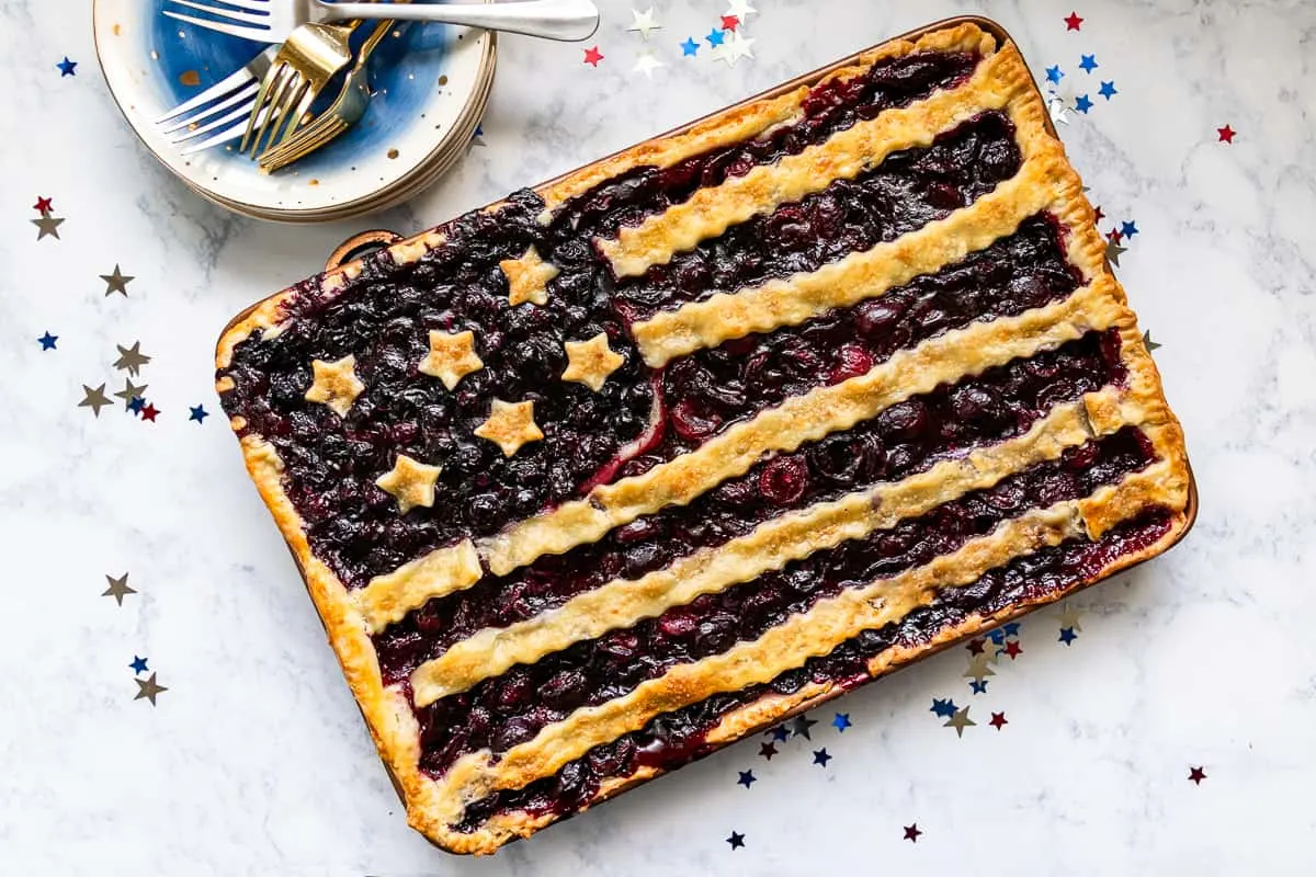 This patriotic blueberry cherry slab pie is a festive way to celebrate summer. Even pie newbies will achieve beautiful results with the easy to follow video tutorial! * Recipe on GoodieGodmother.com #4thofjuly #patrioticdessert #redwhiteandblue #slabpie #cherrypie #summerdessert