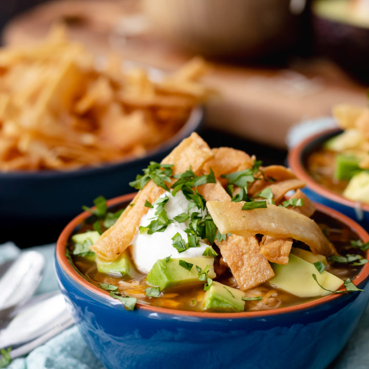 turkey tortilla soup with all the toppings in a blue bowl