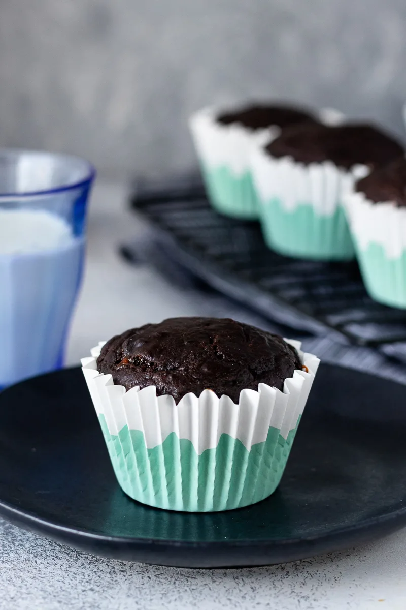 chocolate greek yogurt muffin on a black plate ready to serve in a white and aqua paper muffin liner