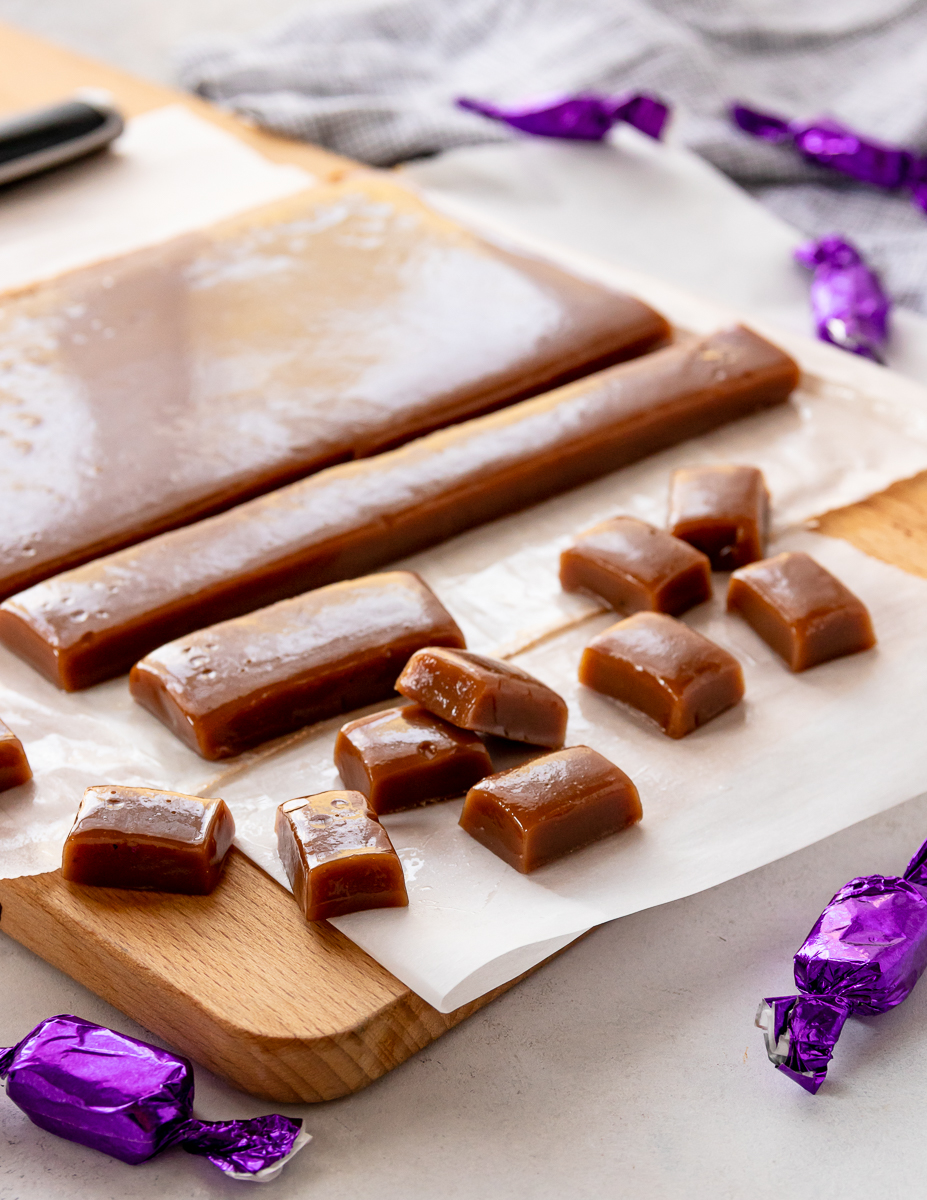 chai tea caramels on a cutting board. some are wrapped, others are not