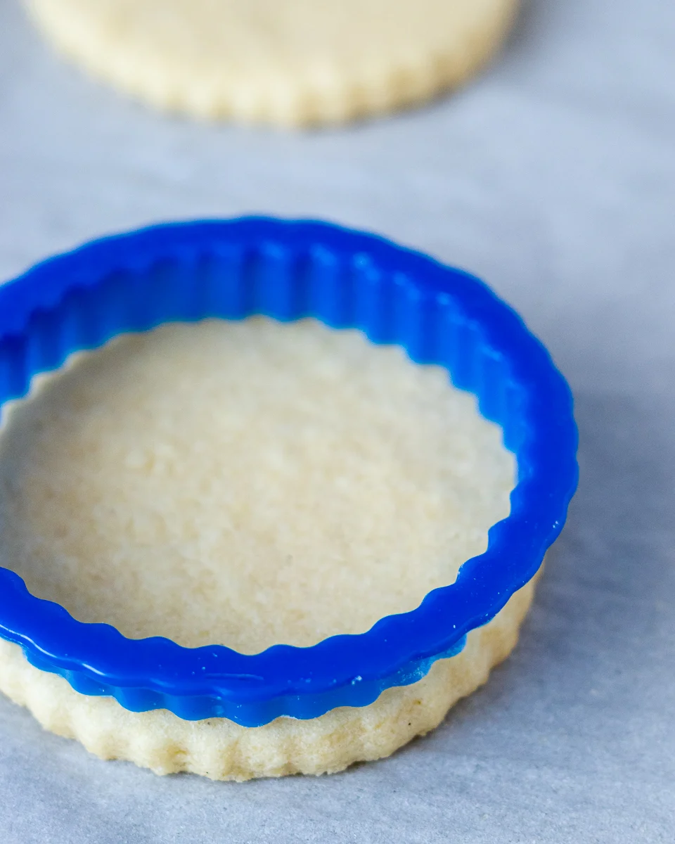 angled picture of the no chill sugar cookie recipe to show it doesn't spread. A blue circle cookie cutter with fluted edges sitting on a baked sugar cookie