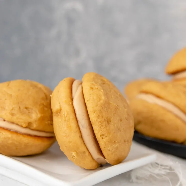 close up of the pumpkin whoopie pies to show layers. pies arranged on a white plate with a grey mottled background
