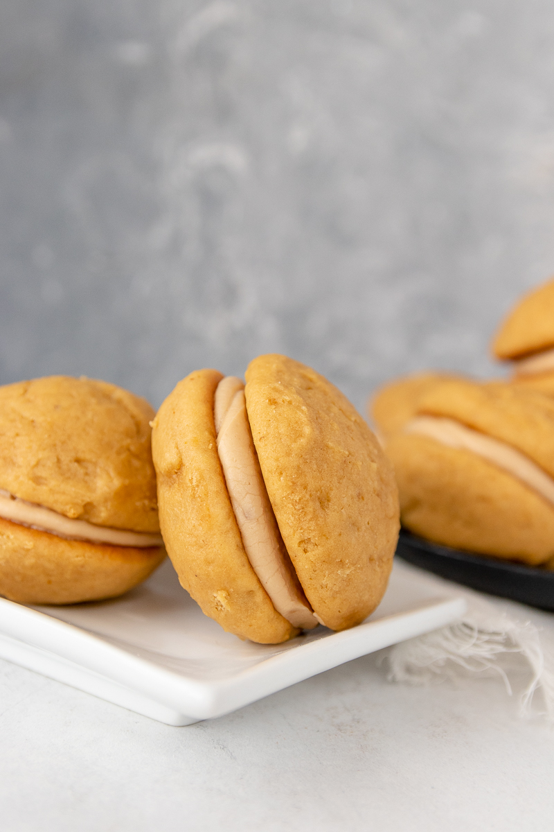 close up of the pumpkin whoopie pies to show layers. pies arranged on a white plate with a grey mottled background