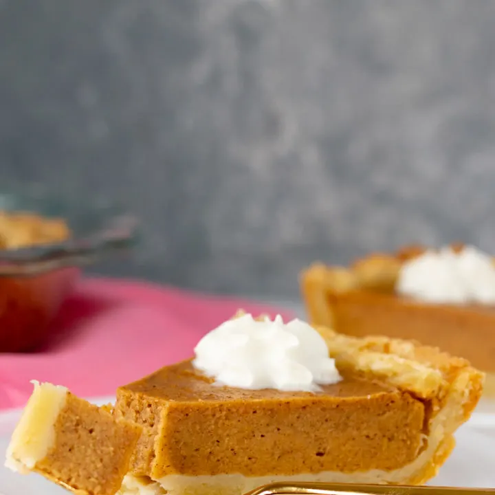 homemade sweet potato pie on a white plate with a mottled grey background