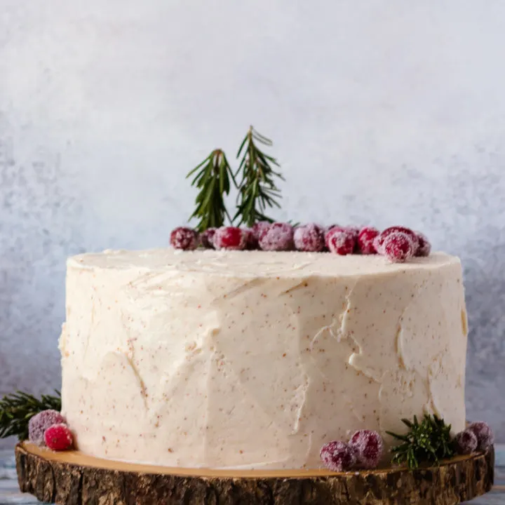 eggnog cake on a wooden cake plate with a mottled grey background