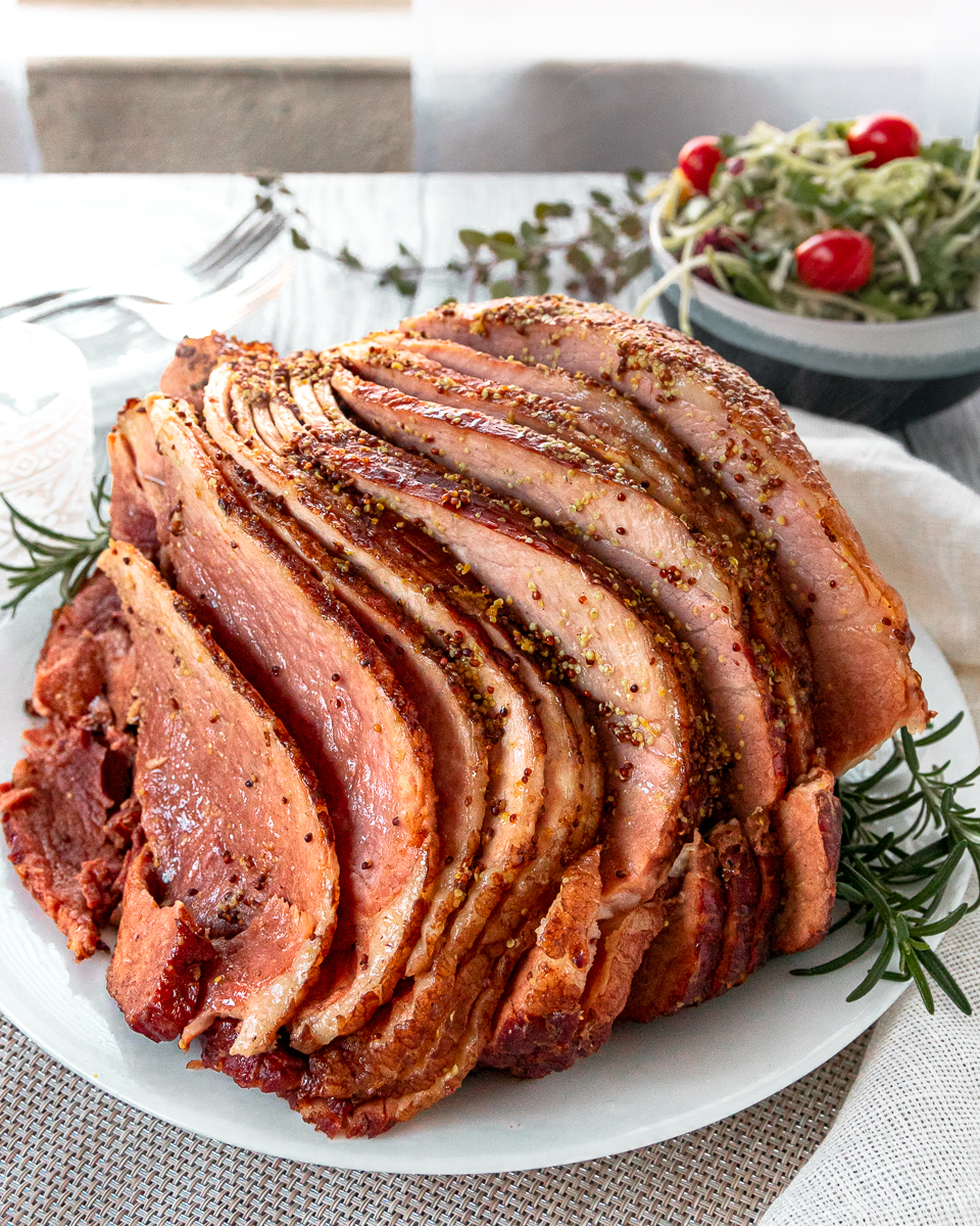 coca-cola slow cooker ham on a white platter garnished with rosemary