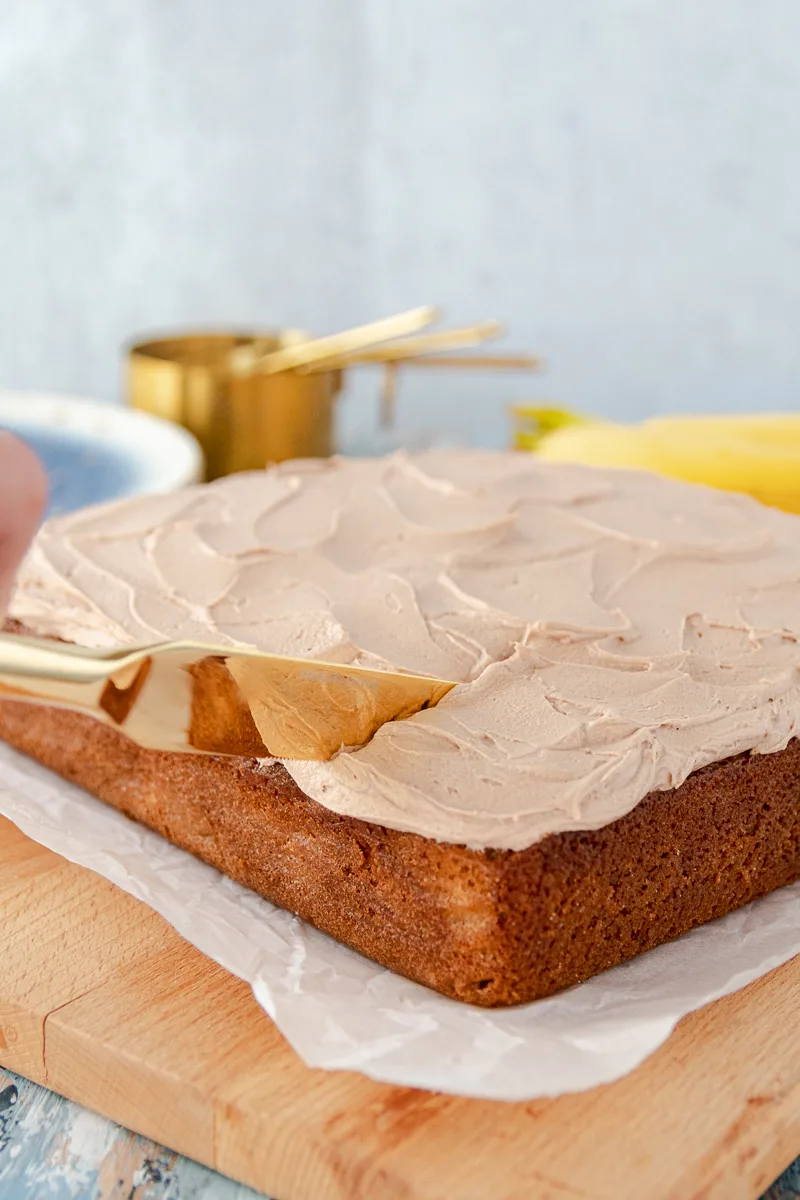gold knife slicing into the banana snack cake with nutella buttercream frosting