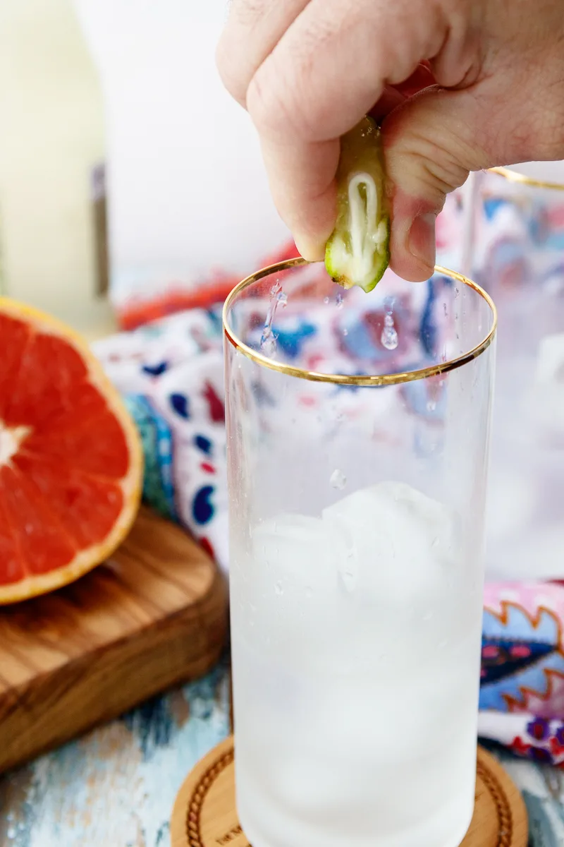 squeezing fresh lime into a paloma cocktail