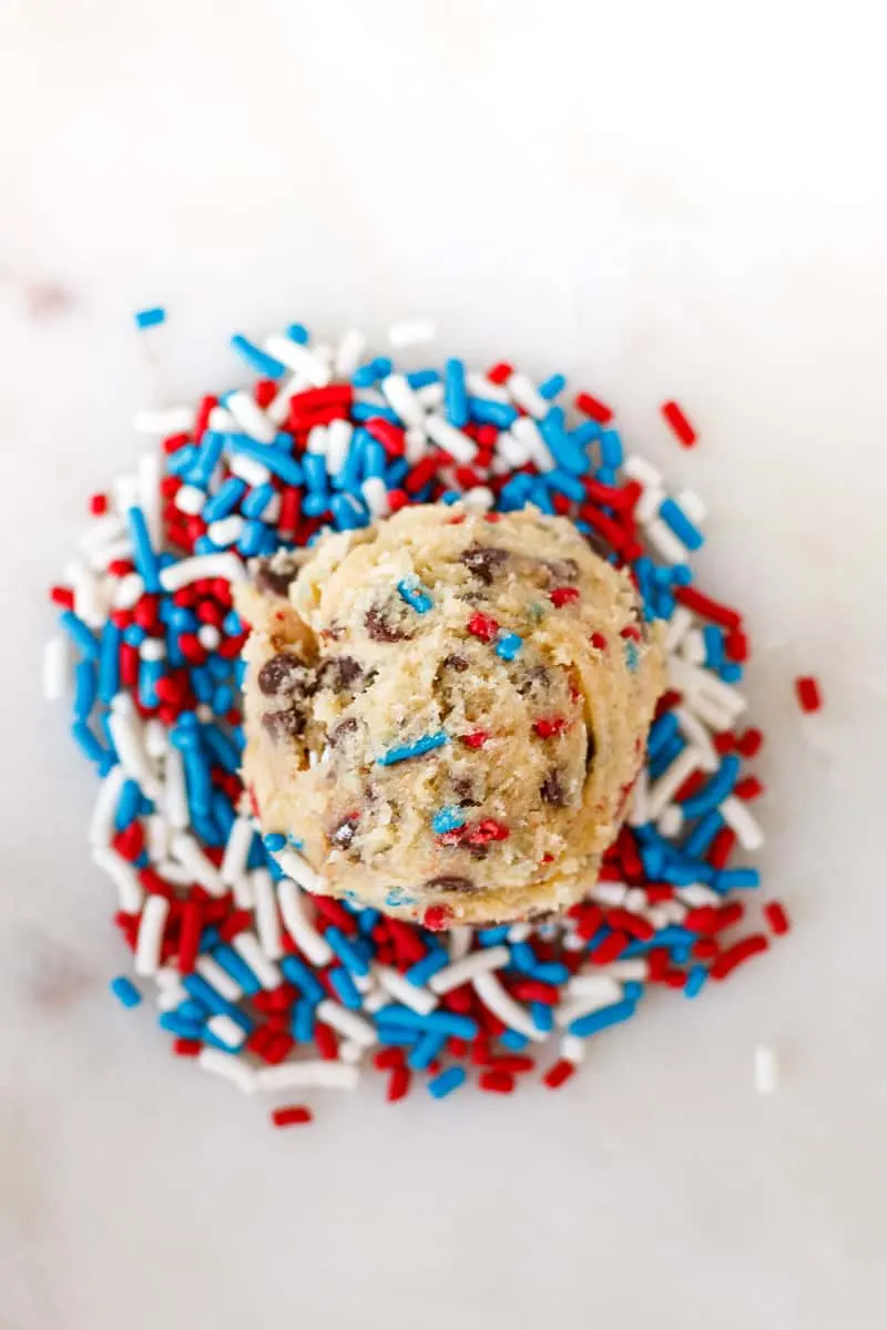 top view of a scoop of patriotic edible cookie dough sitting on a small pile of sprinkles... because sprinkles.