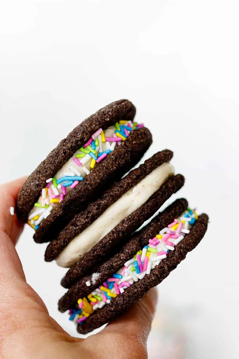 Three root beer float ice cream sandwiches being held against a light background