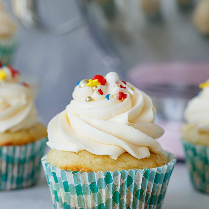 cupcake topped with a swirl of white American buttercream frosting and red, yellow and blue sprinkles