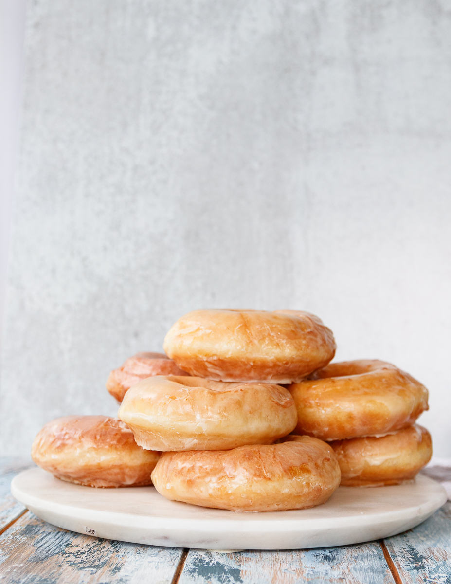 sourdough discard donuts stacked on a white marble tray with a light grey background