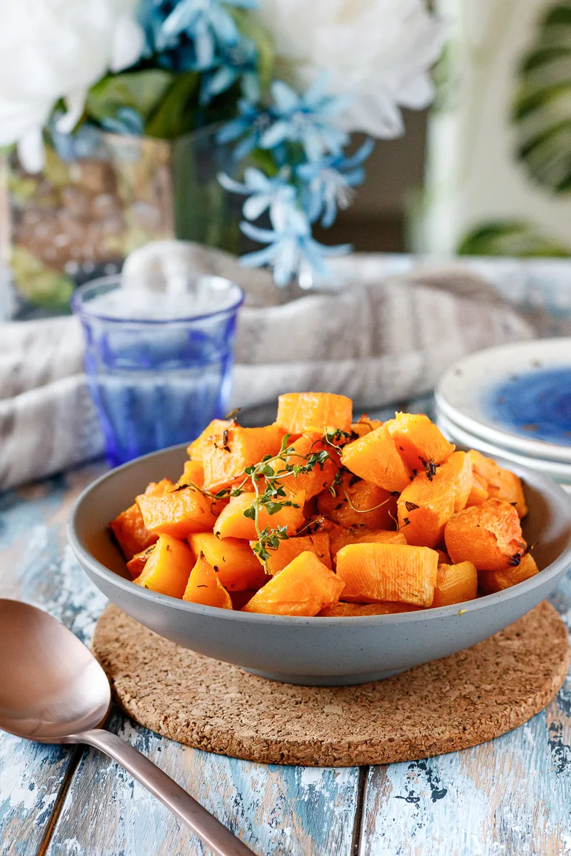 bowl of butternut squash on a styled table with blue tones and a leaf-print chair in the background