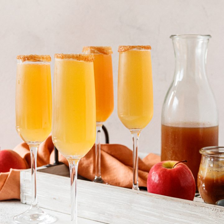 caramel apple cider mimosas shown ready to serve with a light wooden tray in the background
