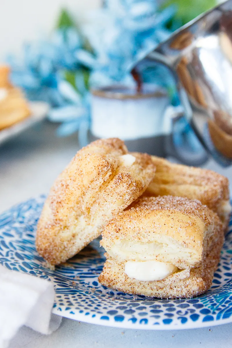 quick puff pastry churro cheesecake bites on a plate with flowers and espresso in the background
