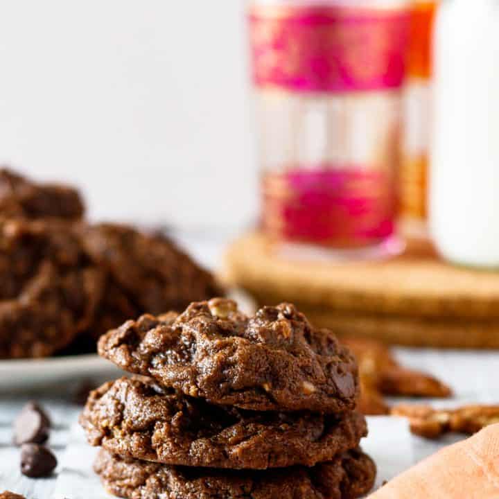 double chocolate pecan toffee cookies stacked with a platter in the background
