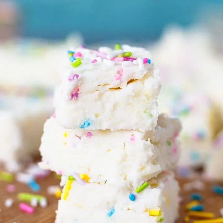 3 stacked squares of two ingredient fudge on a cutting board with scattered sprinkles