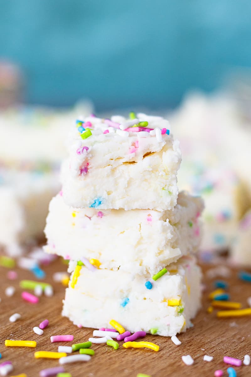3 stacked squares of two ingredient fudge on a cutting board with scattered sprinkles