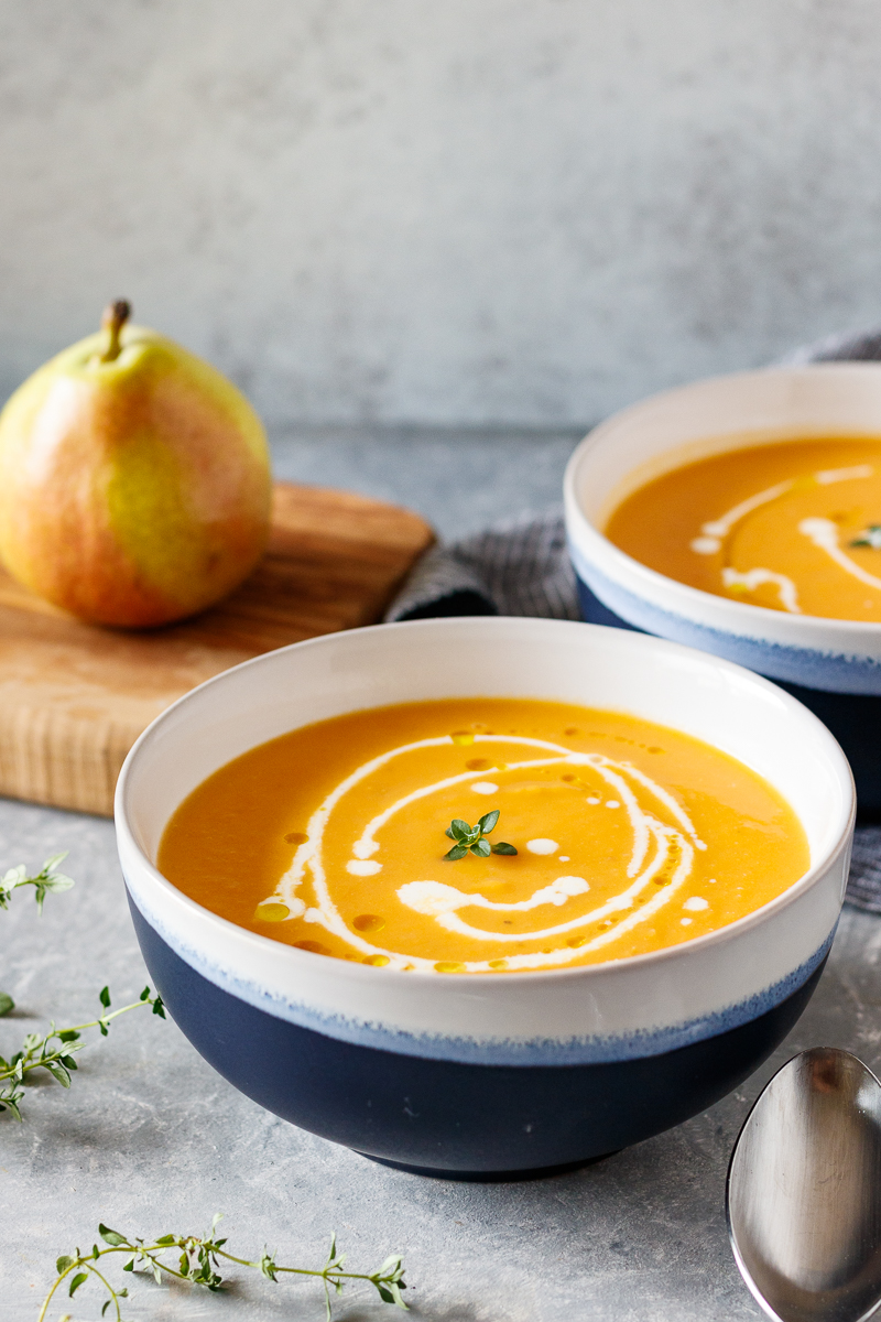 pear and sweet potato soup in blue and white bowls with a drizzle of heavy cream to add fancy detailing