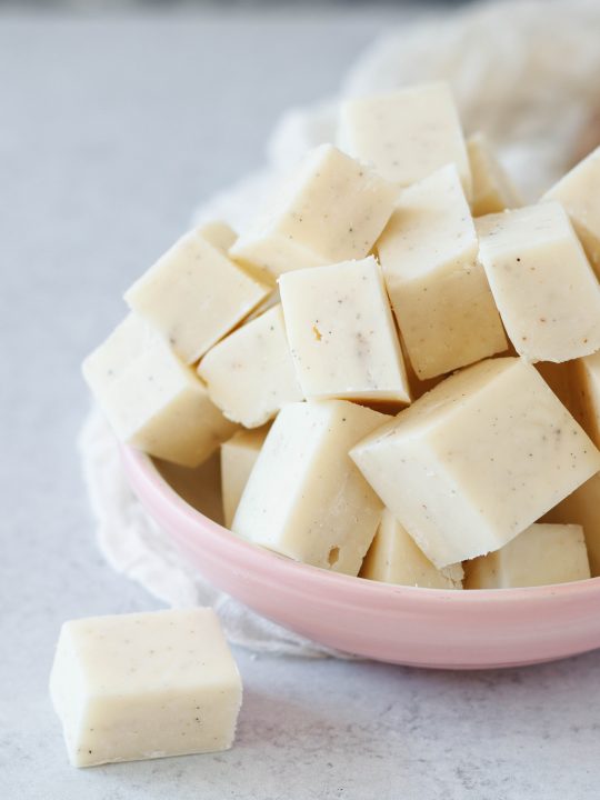 closeup of the easy cardamom fudge, cut into pieces and piled in a pale pink bowl
