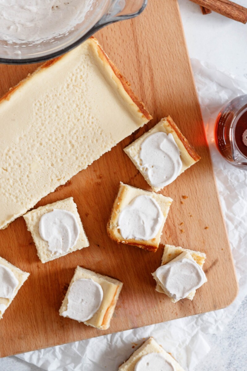 maple cheesecake bars flat lay photo with most of the cut bars sitting on a cutting board