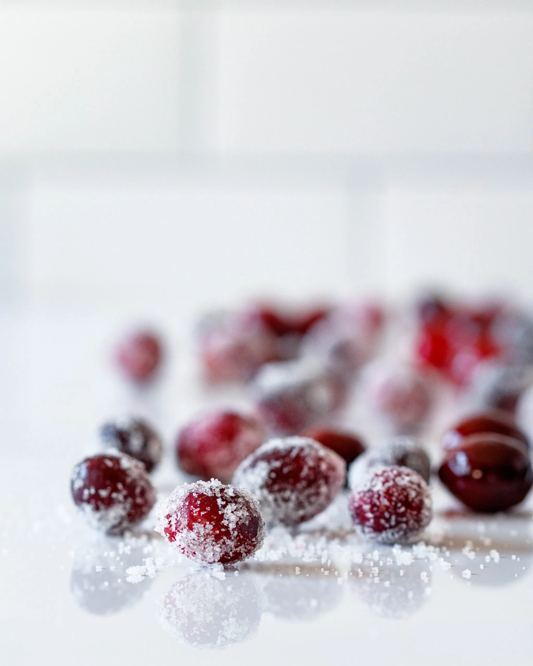 a few scattered cranberries on a white surface - some coated, some uncoated