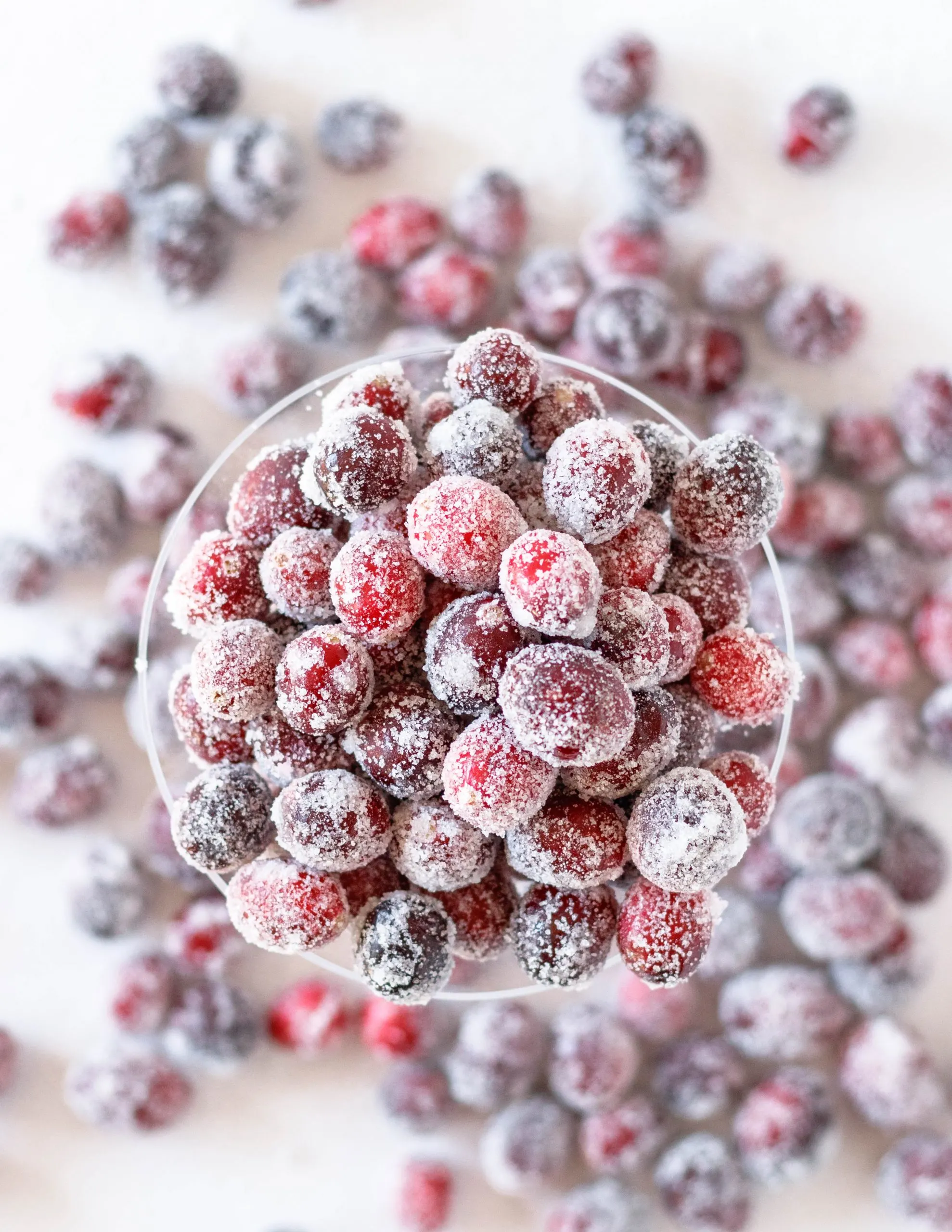 top view of the sugared cranberries in a glass on a white table