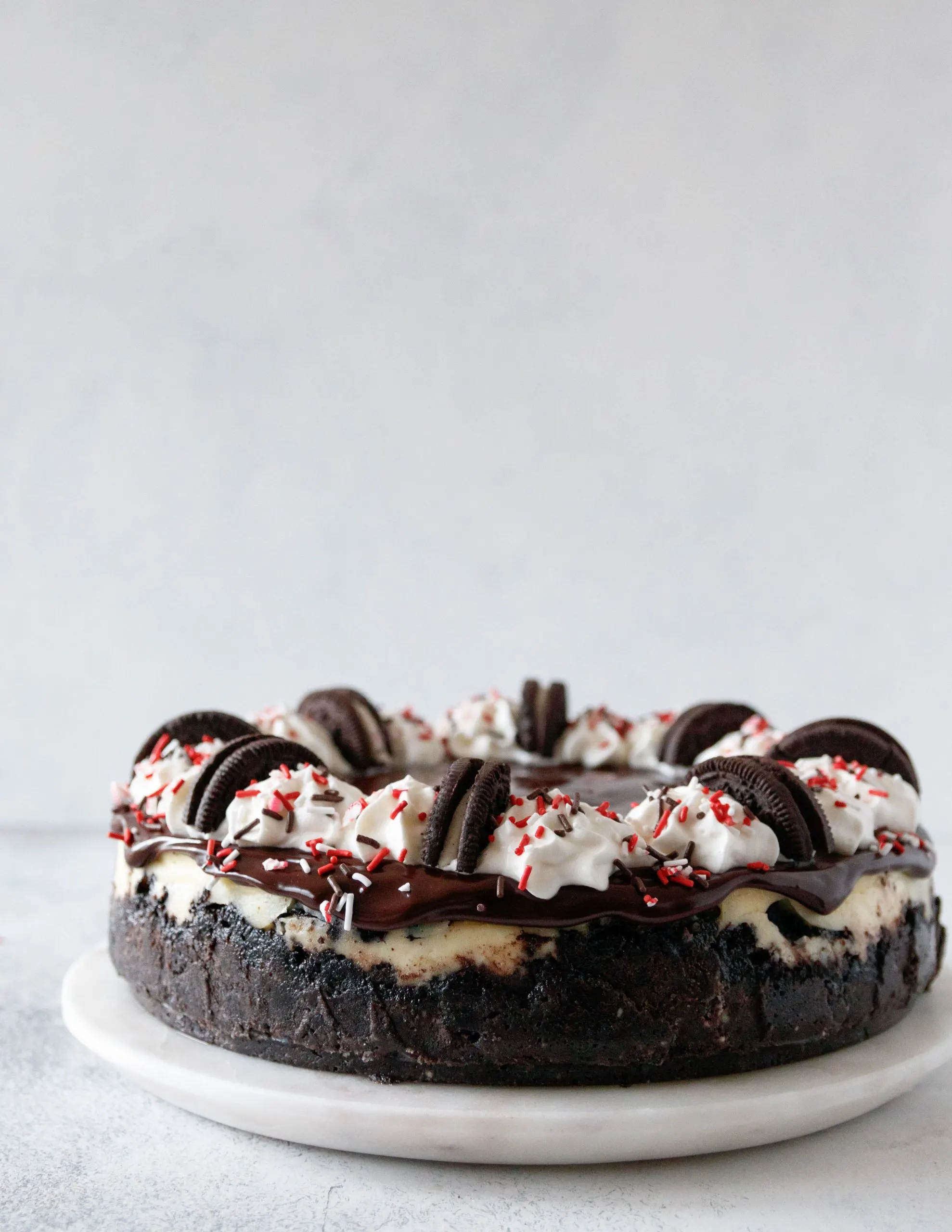 https://goodiegodmother.com/wp-content/uploads/2020/12/cookies-and-cream-cheesecake-candy-cane-joe-joe-cheesecake-recipe-scaled.jpg.webp