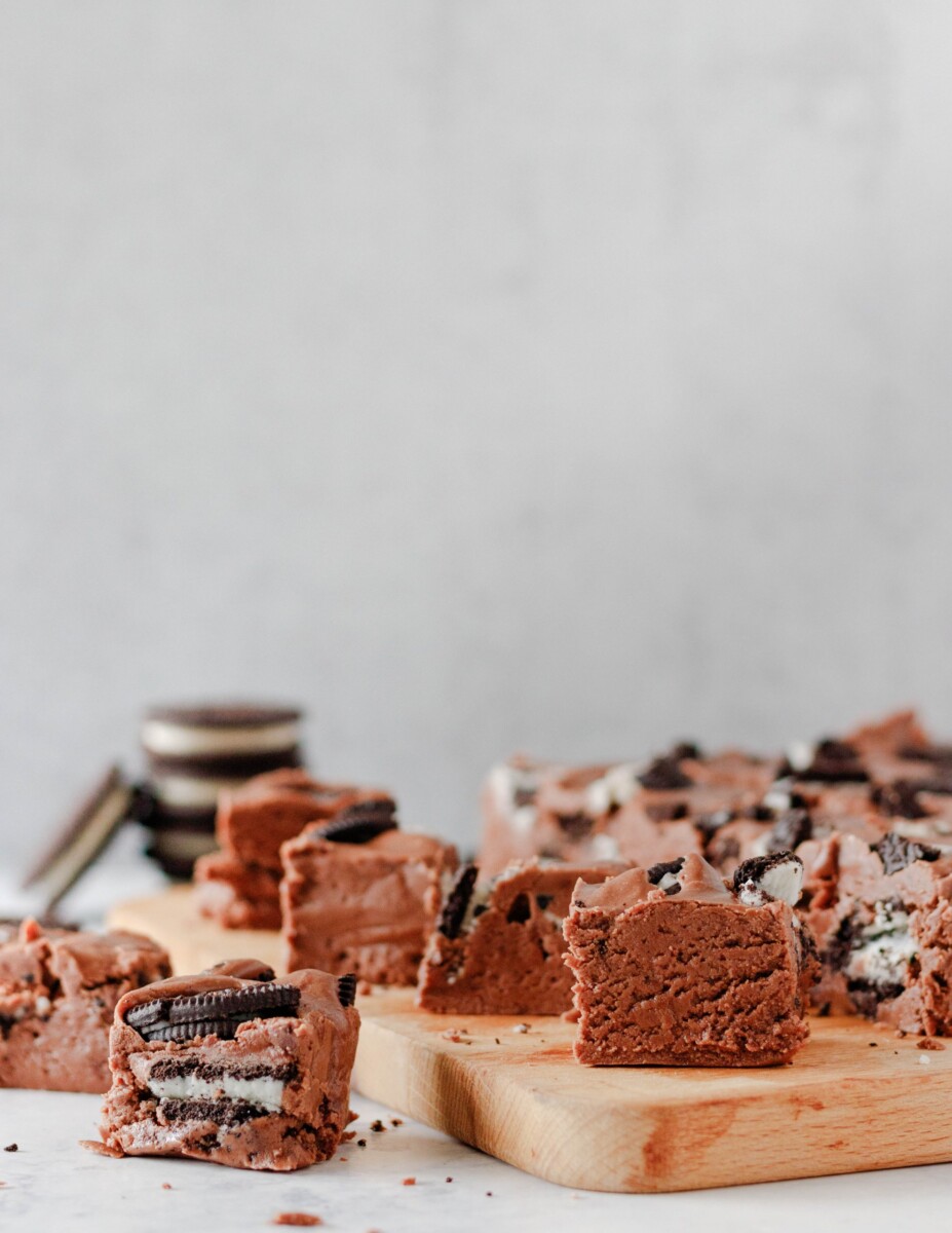 cut double chocolate oreo fudge squares with a light background and sitting on a wooden cutting board