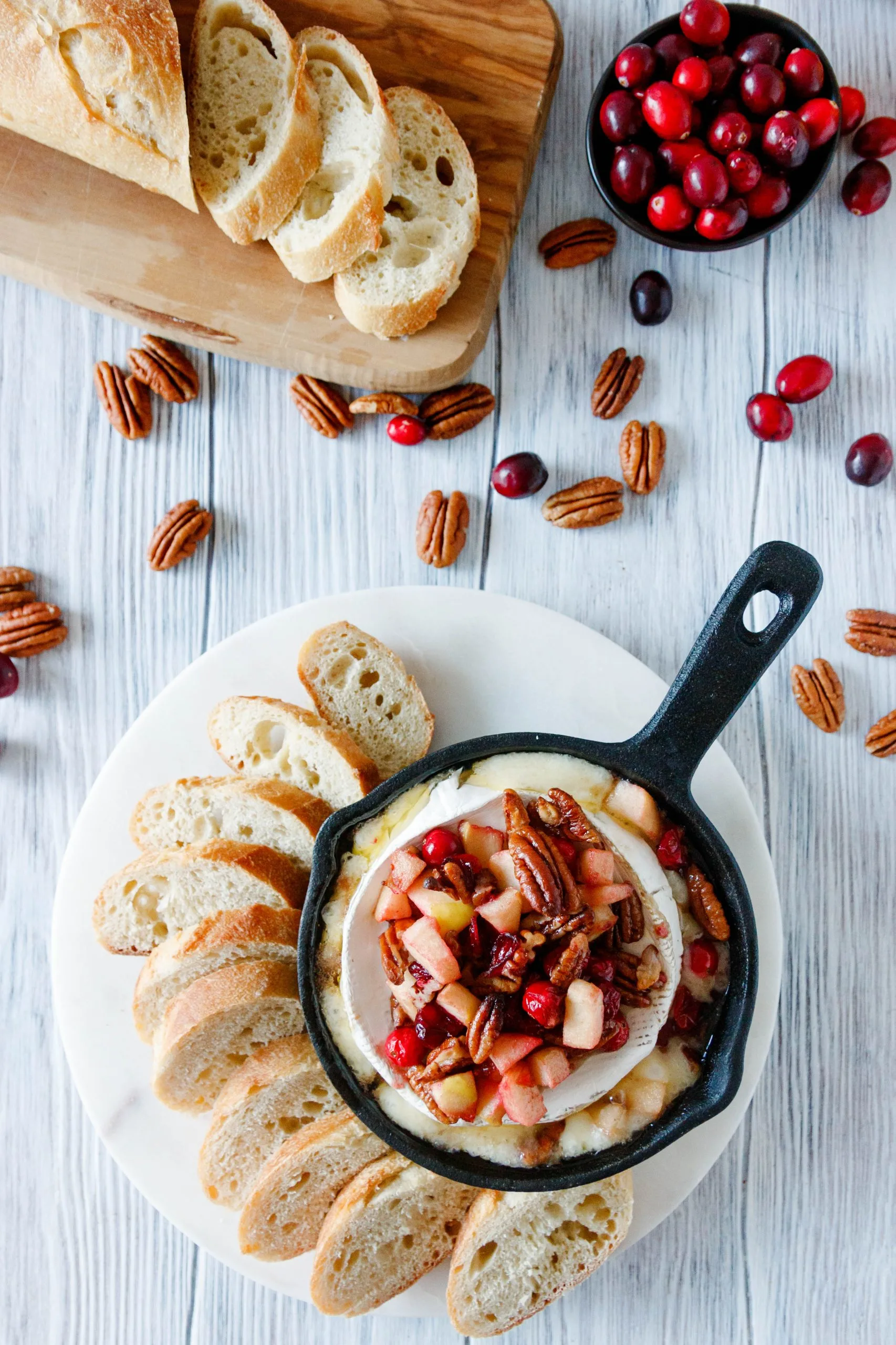 flat lay image of the baked brie with scattered pecans and cranberries