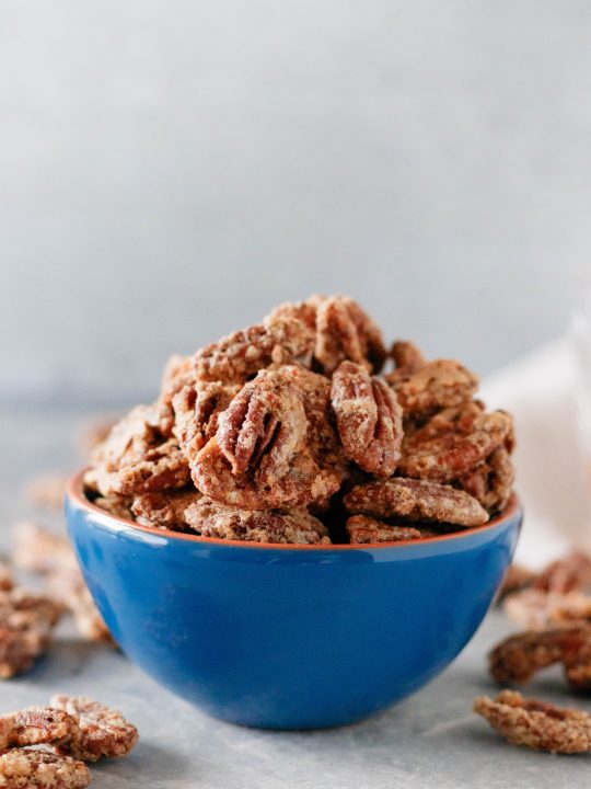 whiskey candied pecans in a blue bowl with a light background