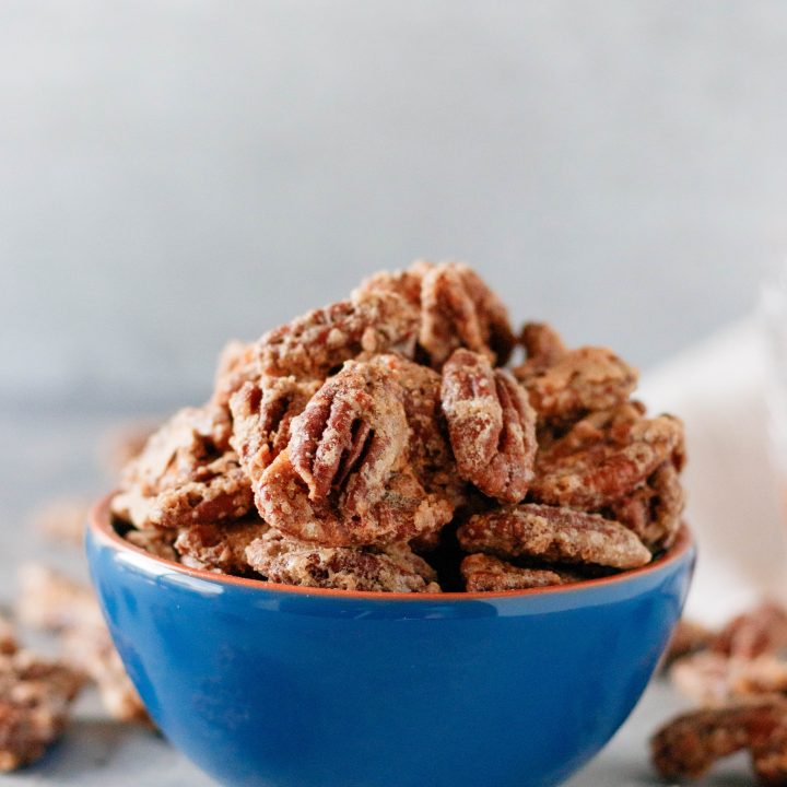 whiskey candied pecans in a blue bowl with a light background