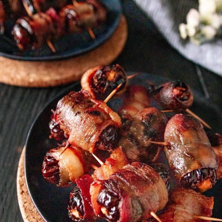 angled shot of a plate of goat cheese stuffed dates wrapped in bacon