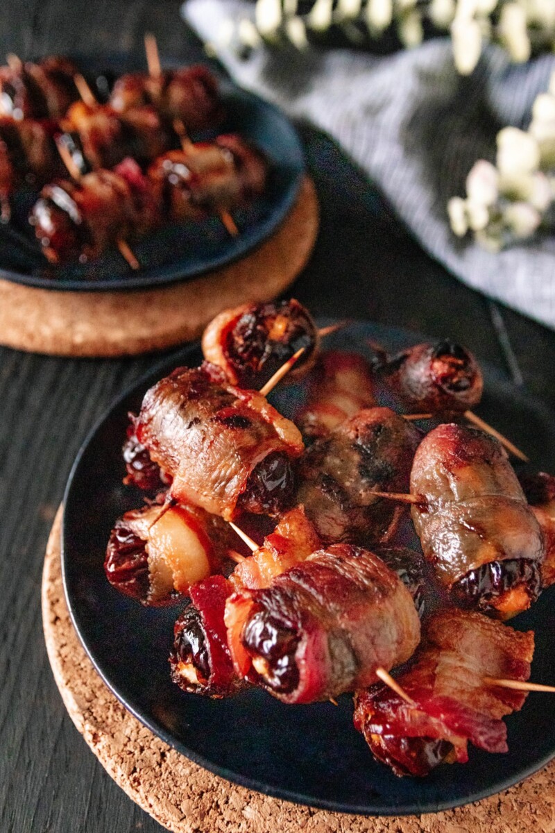 angled shot of a plate of goat cheese stuffed dates wrapped in bacon 