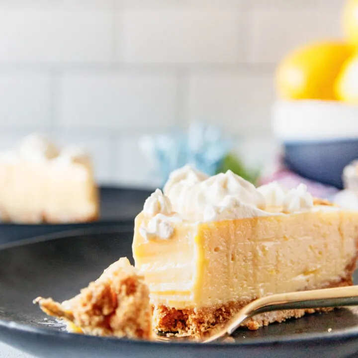 close up picture of a slice of creamy lemon pie with a bite cut out of it. This shows the smooth texture of the pie filling and the contrast with a par-baked graham cracker crust