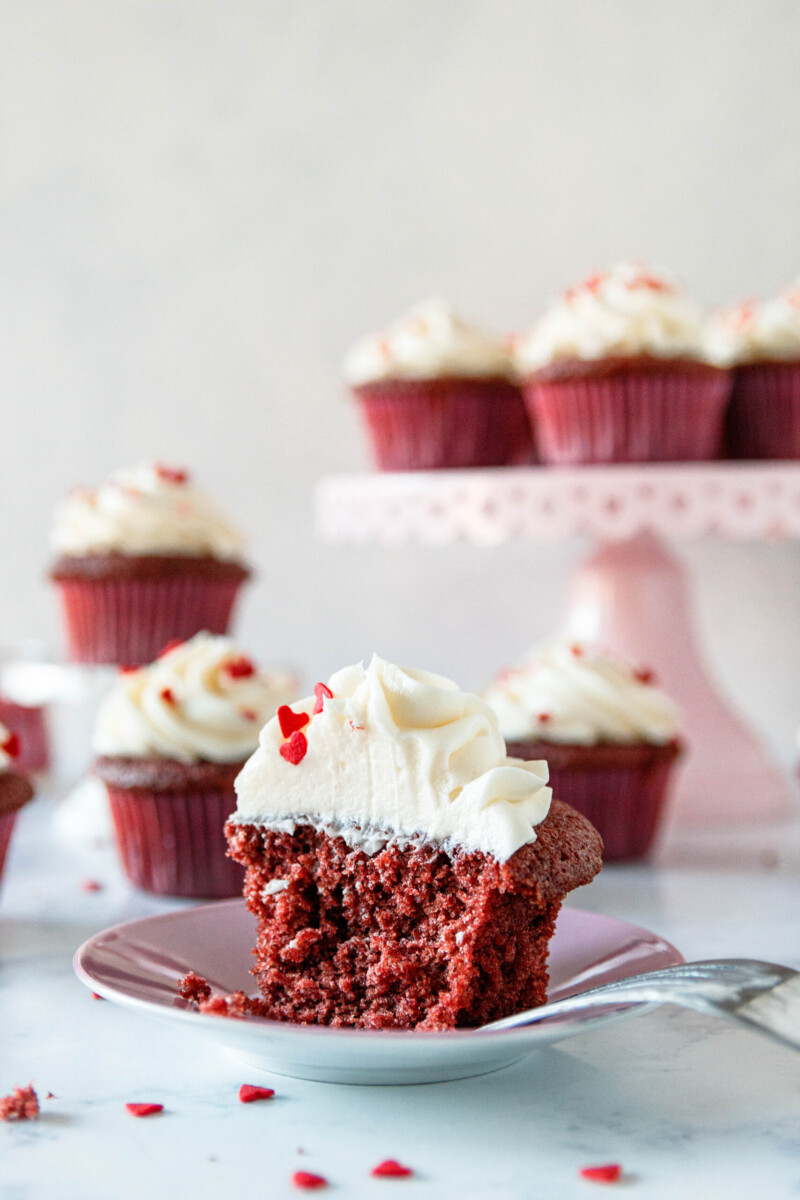 cut red velvet cupcake on a mauve plate to show the moist and fluffy crumb