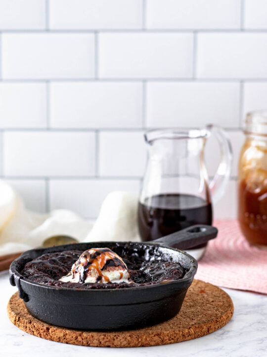 hot fudge cake sitting on a cork trivet with a white subway tile background