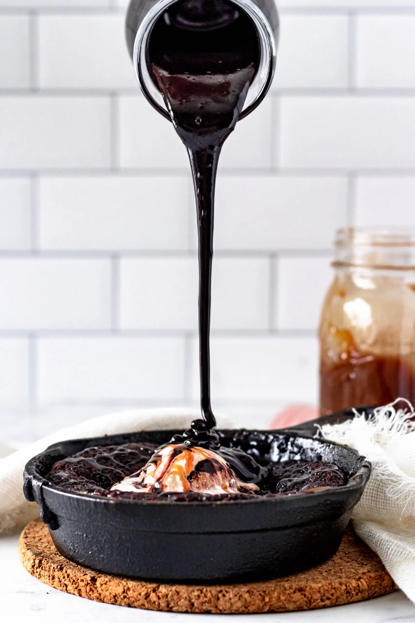 chocolate syrup pouring onto the hot fudge cake