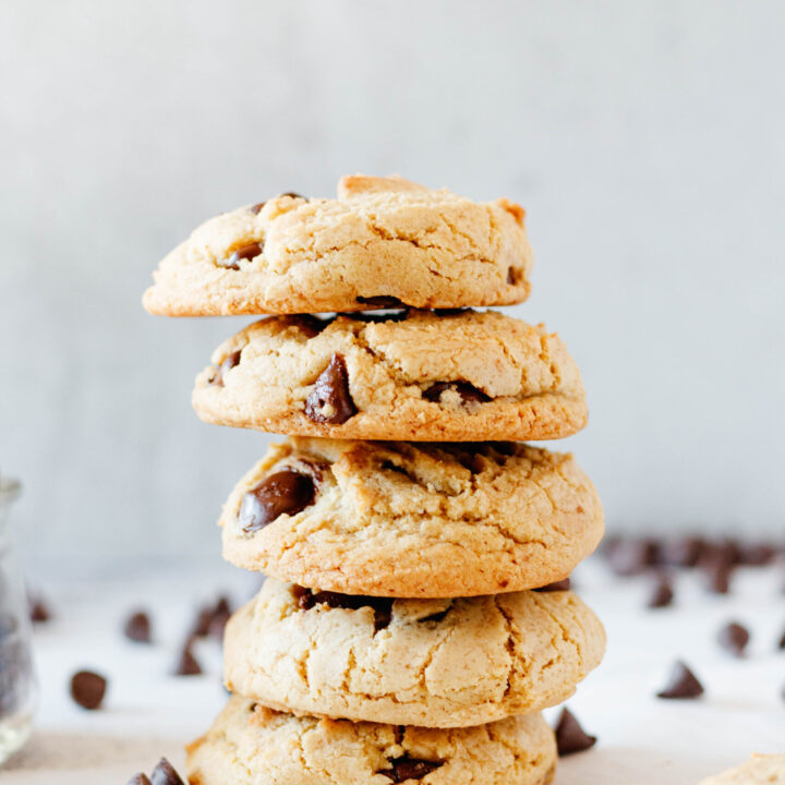 stack of 5 chocolate chip cookies with scattered chocolate chips around the stack