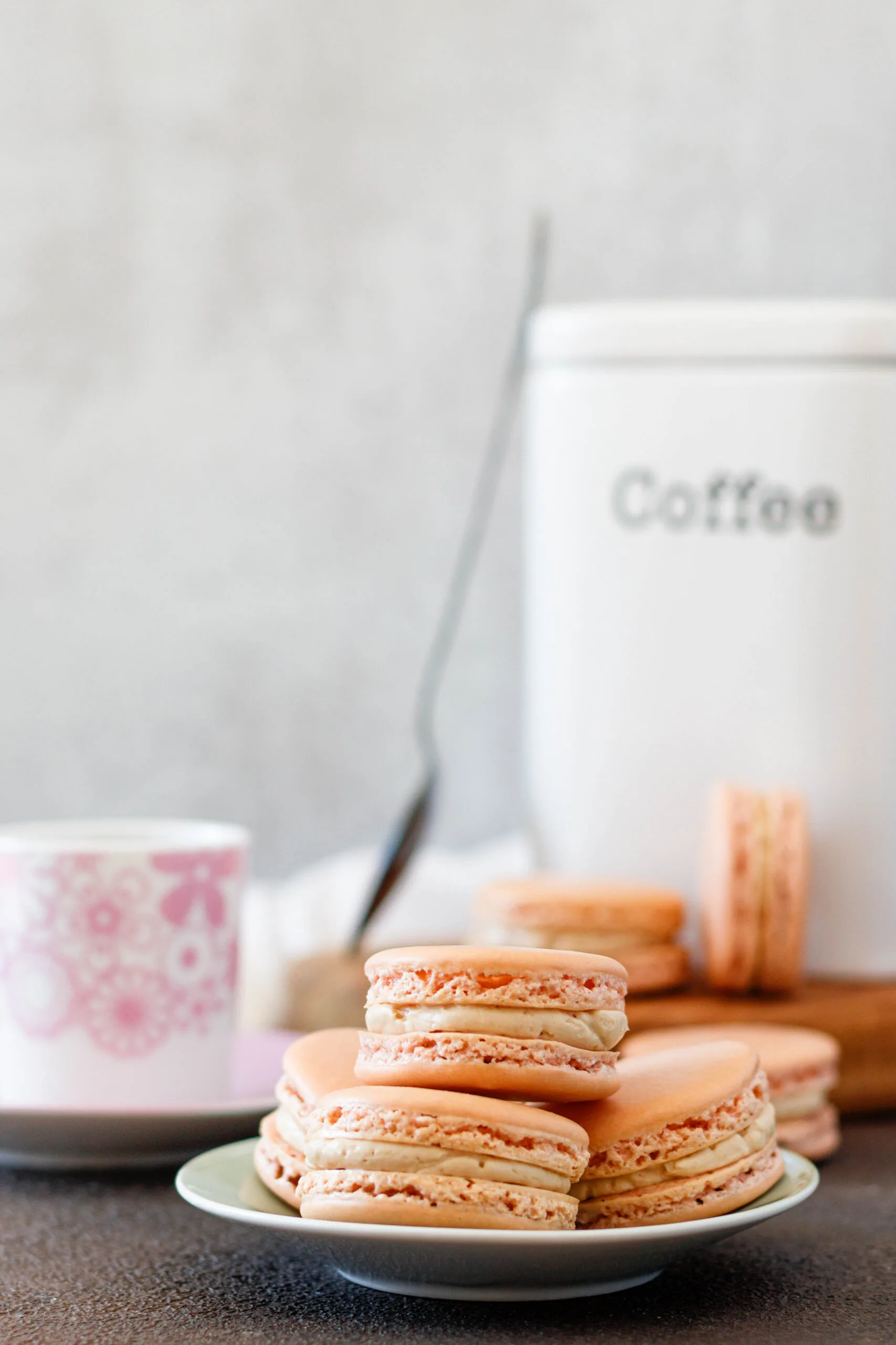 macarons on a serving plate with a cannister of coffee in the background