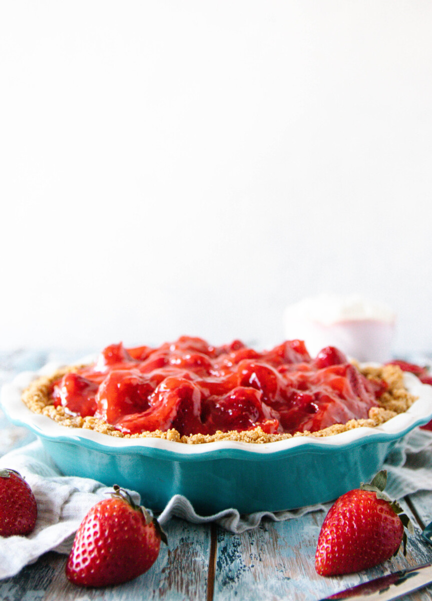 whole fresh strawberry pie in a blue pie dish on a mottled blue surface