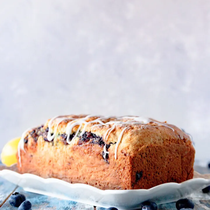 unsliced lemon blueberry swirl bread on a white plate with scalloped edges