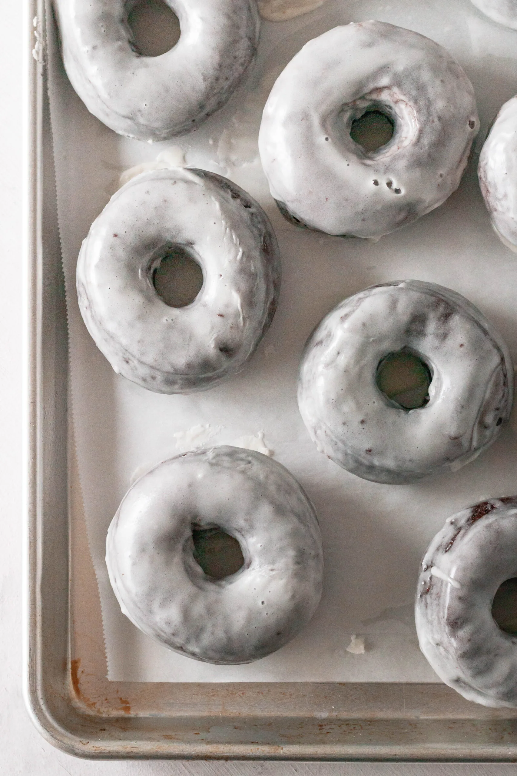 top view of the glazed donuts setting on a baking sheet